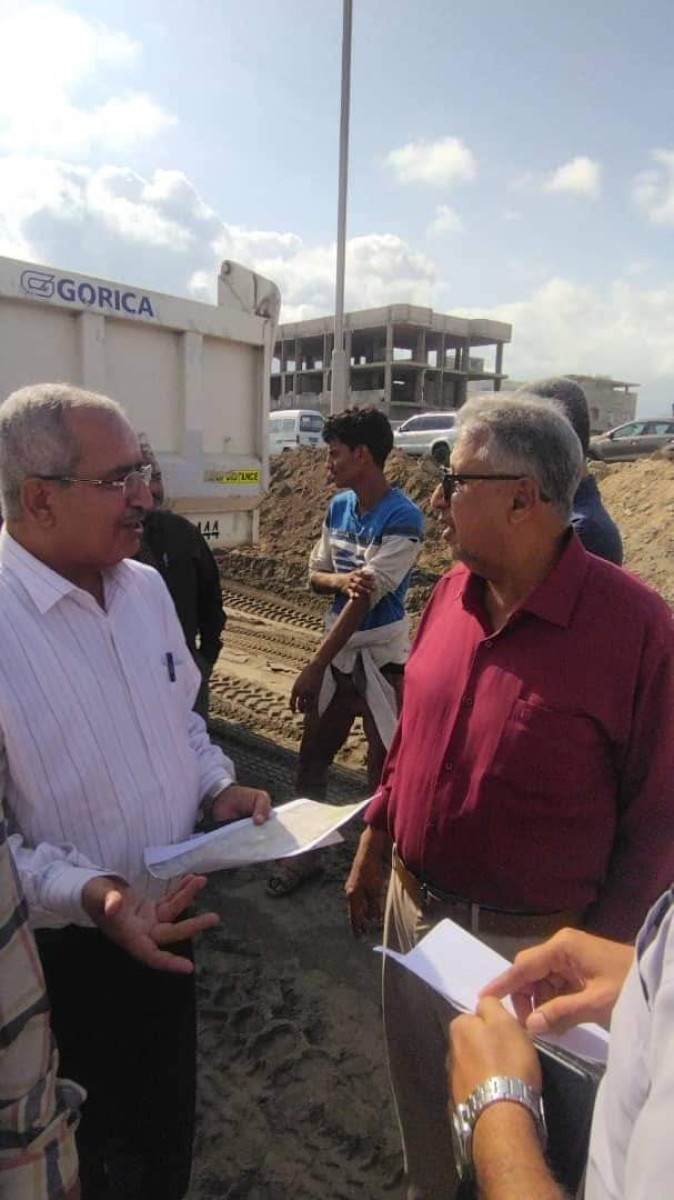 A government delegation reviews the progress of work on the project to remove waste and dust from the lake in Khor Maksar